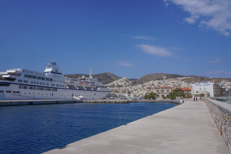 Hermoupolis, Syros, Greece: A cruise ship docks at the harbor in Syros, with the two hills of the...