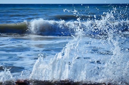 Powerful waves of the sea foaming, breaking against the rocky shoreの写真素材