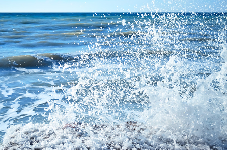 Powerful waves of the sea foaming, breaking against the rocky shoreの写真素材