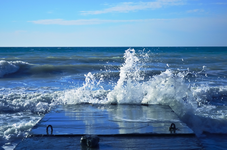 Powerful waves of the sea foam, breaking the concrete pierの写真素材