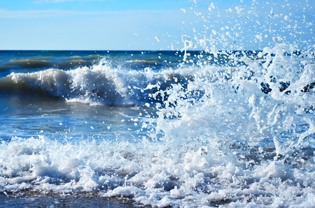 Powerful waves of the sea foaming, breaking against the rocky shoreの写真素材