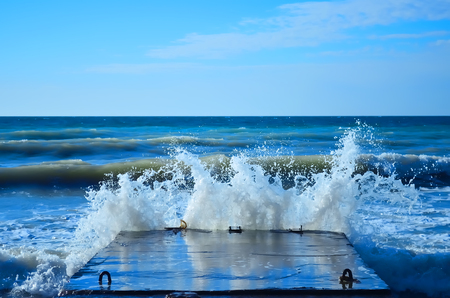 Powerful waves of the sea foam, breaking the concrete pierの写真素材