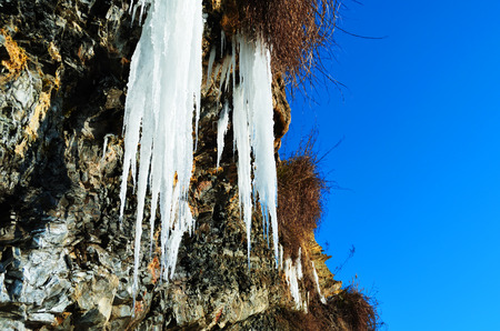 Steep rock with a frozen waterfall near the seaの写真素材