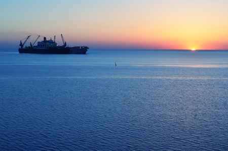 The ship that is laying a gas pipe on the sea bottom against the sunsetの写真素材