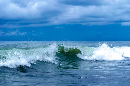 Coastal transparent sea crashing wave with foam on its topの写真素材