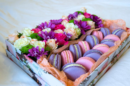 French macaroon cake. Violet and pink macaroons in a box with flowers on the bed.の写真素材