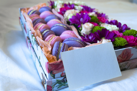 French macaroon cake. Violet and pink macaroons in a box with flowers on the bed.の写真素材