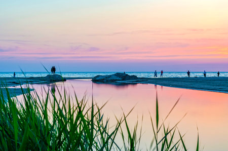 Tourists and fishermen are on the black sea and admire the beautiful sunset. A couple in love takes a selfie against the sunset.の写真素材