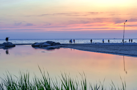 Tourists and fishermen are on the black sea and admire the beautiful sunset.の写真素材