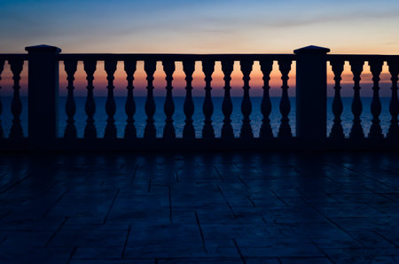 Beautiful seascape and fence with old classic white balusters, The evening sun shines through the...
