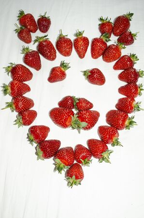 Ripe strawberries are laid out on a white background in the shape of a lion's faceの写真素材