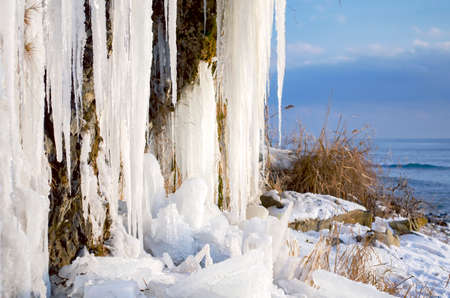 Huge icicles hanging from the rocks, frozen waterfall with views of the seaの写真素材
