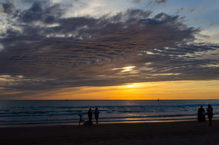 Family walk on the beach at sunsetの写真素材