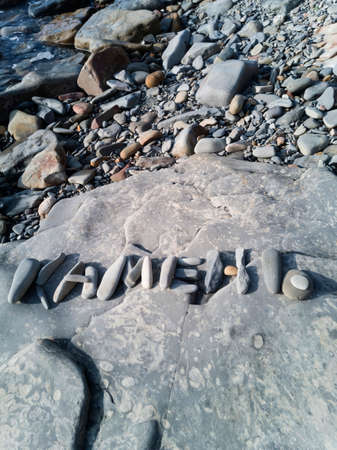On a large stone on the seashore, the inscription "Stone" is laid out in Russian lettersの写真素材