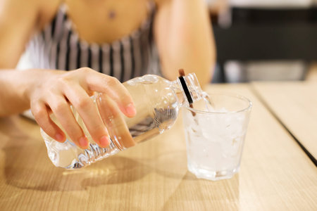 Young woman pouring water from a bottle into glassの写真素材