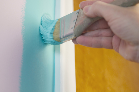 Close-Up Of Hand Holding Brush and Painting Wall Turquoiseの写真素材