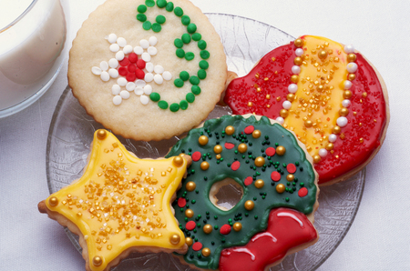 Artistically Decorated Christmas Cut-Out Cookies On Glass Plate With Glass Of Milk, White Backgroundの写真素材