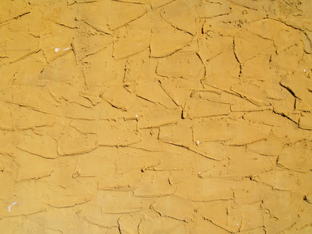 Rough textured concrete or stucco exterior wall painted a gold color.   