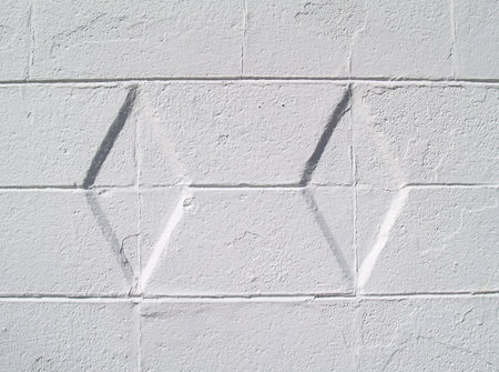 Close-up view of a white painted brick or block exterior wall with diamond texture.      の写真素材