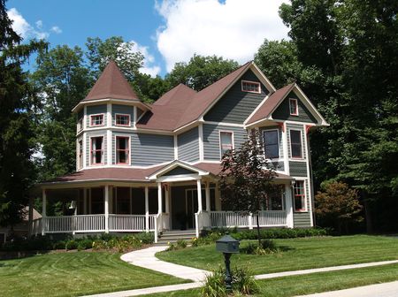 New two story Victorian residential home with vinyl or board siding on the facade styled after an old-fashioned historical house with bay windows, gingerbread and a turret.の写真素材