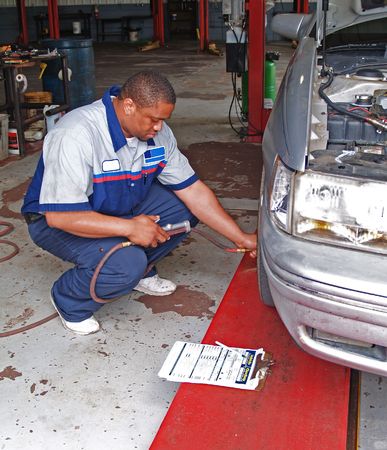 Auto mechanic inspecting a carâs tire pressure in a service garage.の写真素材