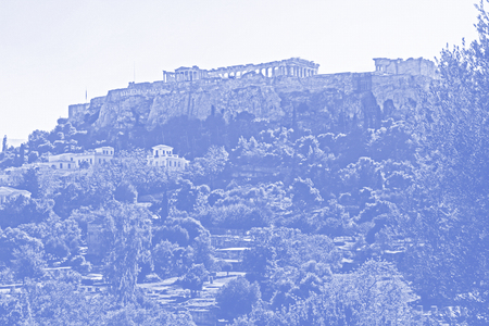 Stylized blue and white image of the Parthenon on the Acropolis in Athens, Greece with a white sky copy space and a beautiful landscape of the neighborhood nearby digitally stylized with digital blue half tone effect.の写真素材