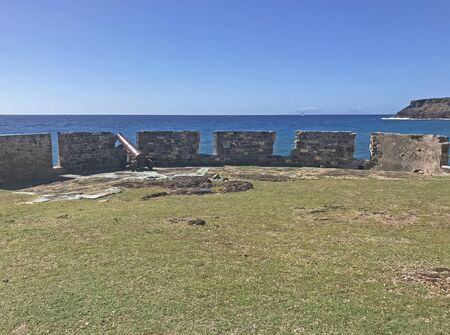 Antigua coastline and outer fort wall with cannon ports as seen from the Fort Berkeley Peninsula in Antigua and Barbuda, Caribbean, Lesser Antilles, West Indies with blue sky copy space.の写真素材