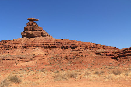 In Monument Valley stands Mexican Hat, red rock formation in Southern Utah, US, San Juan County, on the Navajo Nationâs borders, with blue sky and rocky copy space.の写真素材