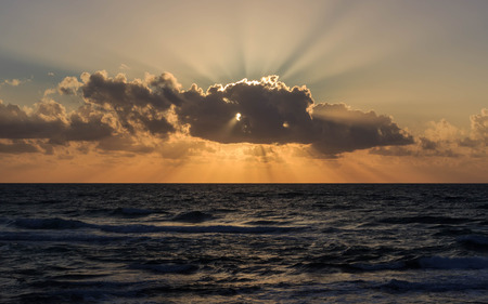 The rays of the setting sun burst out of the cloudの写真素材