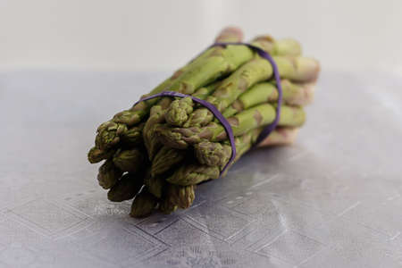knitted bunch of asparagus on a white tableclothの写真素材