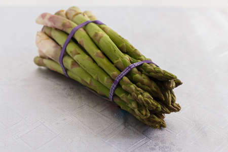 knitted bunch of asparagus on a white tableclothの写真素材