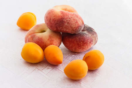 a few peaches and apricots on a white tableclothの写真素材
