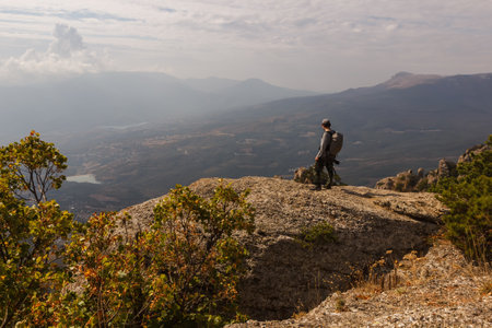 A tourist stands on the rock of the Demerdzhi mountain range with a view of the valleyの写真素材