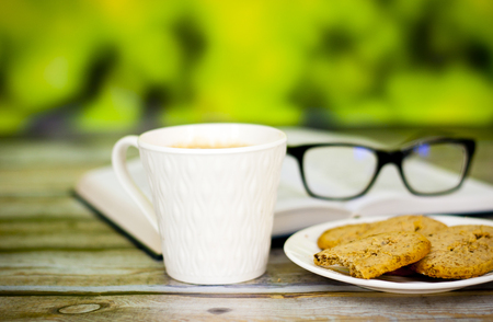 Cup of fresh coffee and book on a wooden tableの写真素材