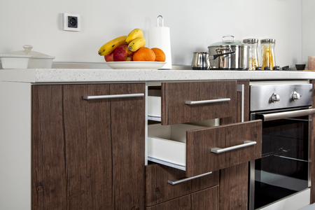 Part of modern kitchen with electric stove oven, drawers, handle and fruitsの写真素材