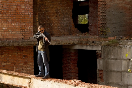 a man with a gun in his hand and a cigarette in the ruins of the houseの写真素材