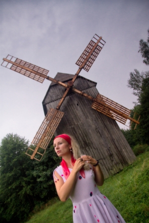 thoughtful young woman standing near a mill with a scarfの写真素材