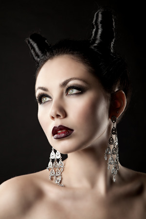 The girl in the image of the demon-tempter and hair in the form of horns. Photo taken in the studio on a background.の写真素材