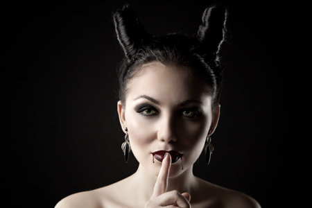 The girl in the image of the demon-tempter and hair in the form of horns. Photo taken in the studio...