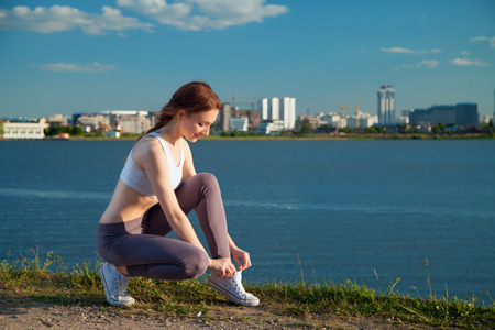 Young sportive woman getting ready to start running workout - Athlete running outdoors at sunset . Attractive girl making sporの写真素材