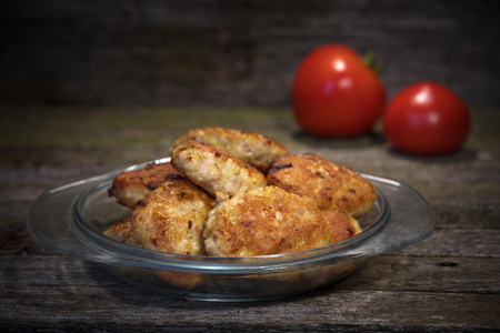 Cutlet and tomato lie on the background of woodの写真素材