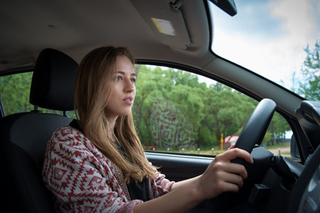 beautiful girl sits behind the wheel of a car