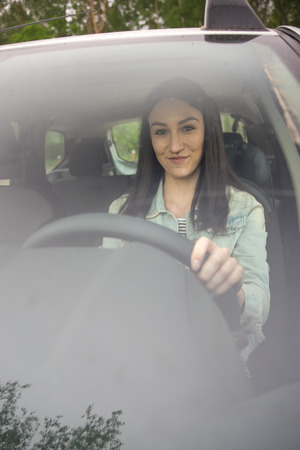 beautiful girl sits behind the wheel of a carの写真素材