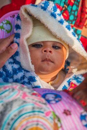 BHAKTAPUR, NEPAL - DECEMBER 14, 2017: a girl in her mother's arms in Durbar Square, Kathmanduのeditorial素材
