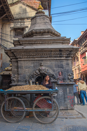 BHAKTAPUR, NEPAL - DECEMBER 14, 2017: A girl in Durbar Square is trading nuts, Kathmanduのeditorial素材