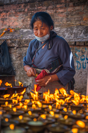 KATMANDU, NEPAL - DECEMBER 19, 2017: A woman is standing at a table with candles in the street, Kathmanduのeditorial素材