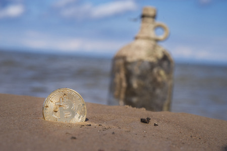treasure from bitcoin on background of bottle with money on the beachの写真素材