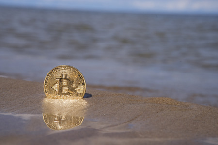 bitcoin on the beach in the sand against the seaの写真素材