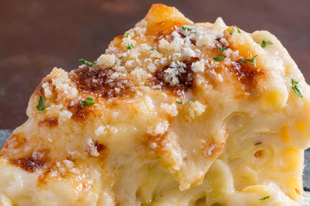 Closeup macro cheesy baked macaroni and cheese pasta portion with parmesean sprinkled on topの写真素材