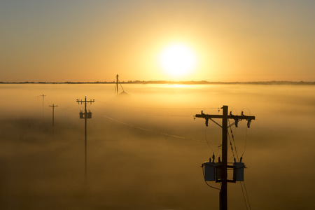 Telephone poles on a foggy misty morning at sunrise or sunset on a rural countryside farmの写真素材
